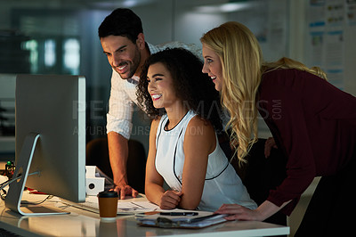 Buy stock photo Shot of a group of young colleagues using a computer together during a late night at work