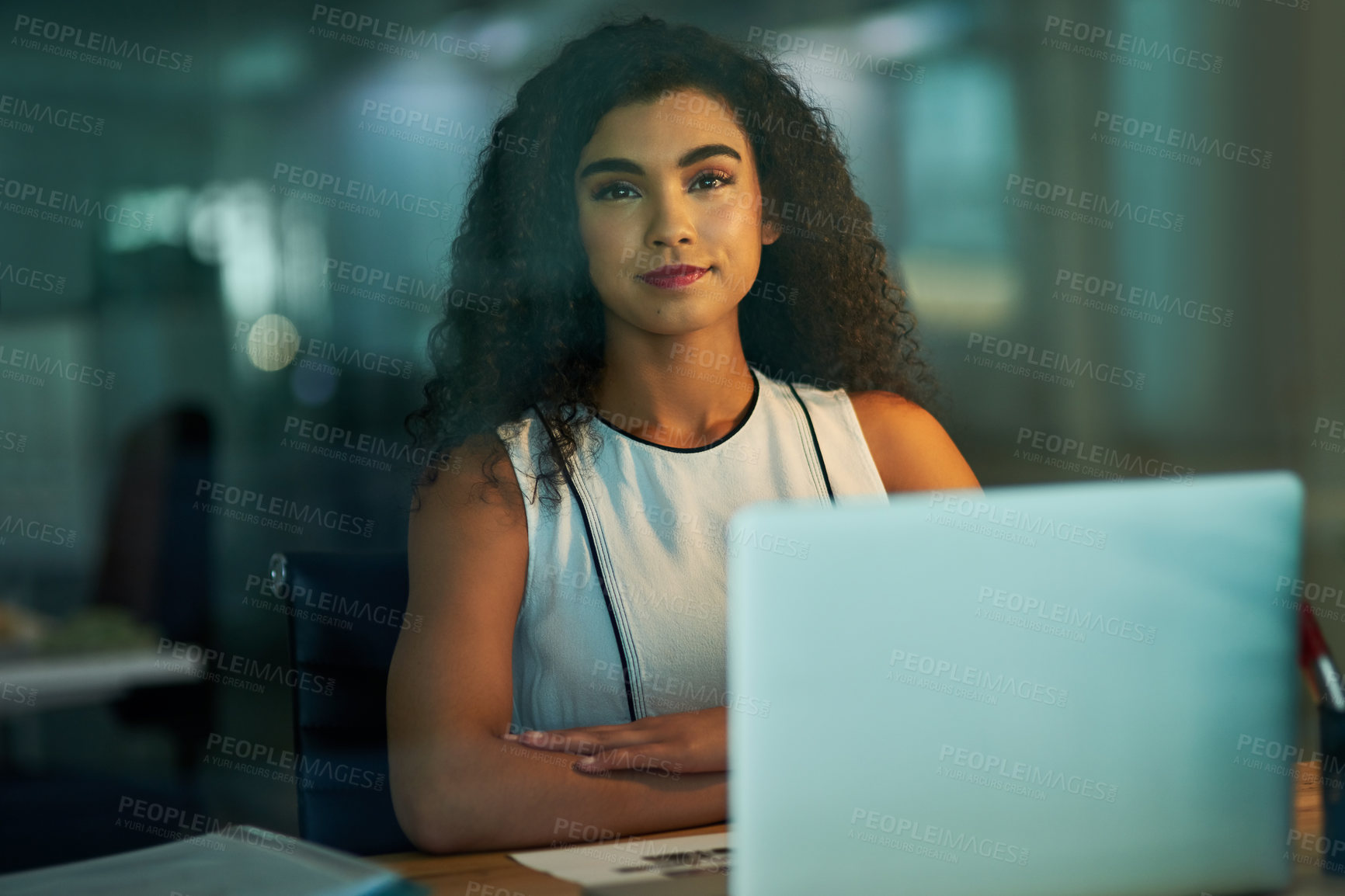 Buy stock photo Portrait of a confident young businesswoman working at her desk at night