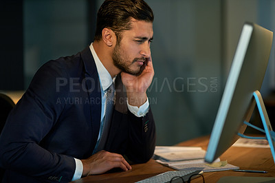 Buy stock photo Shot of a young businessman straining his eyes while using a computer during a late night at work