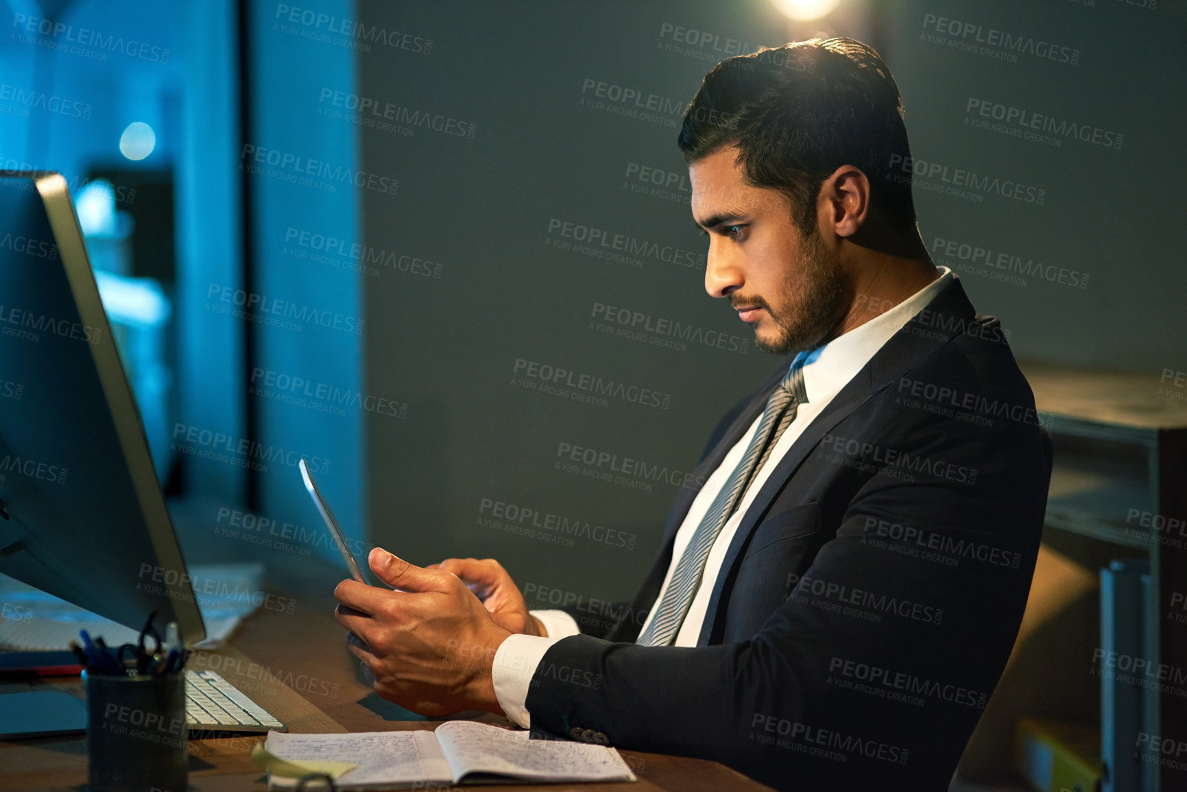 Buy stock photo Businessman, office and phone by table at night for career, advocate or lawyer with research. Male person, computer and mobile by desk for work at law firm, plan for justice or court with technology