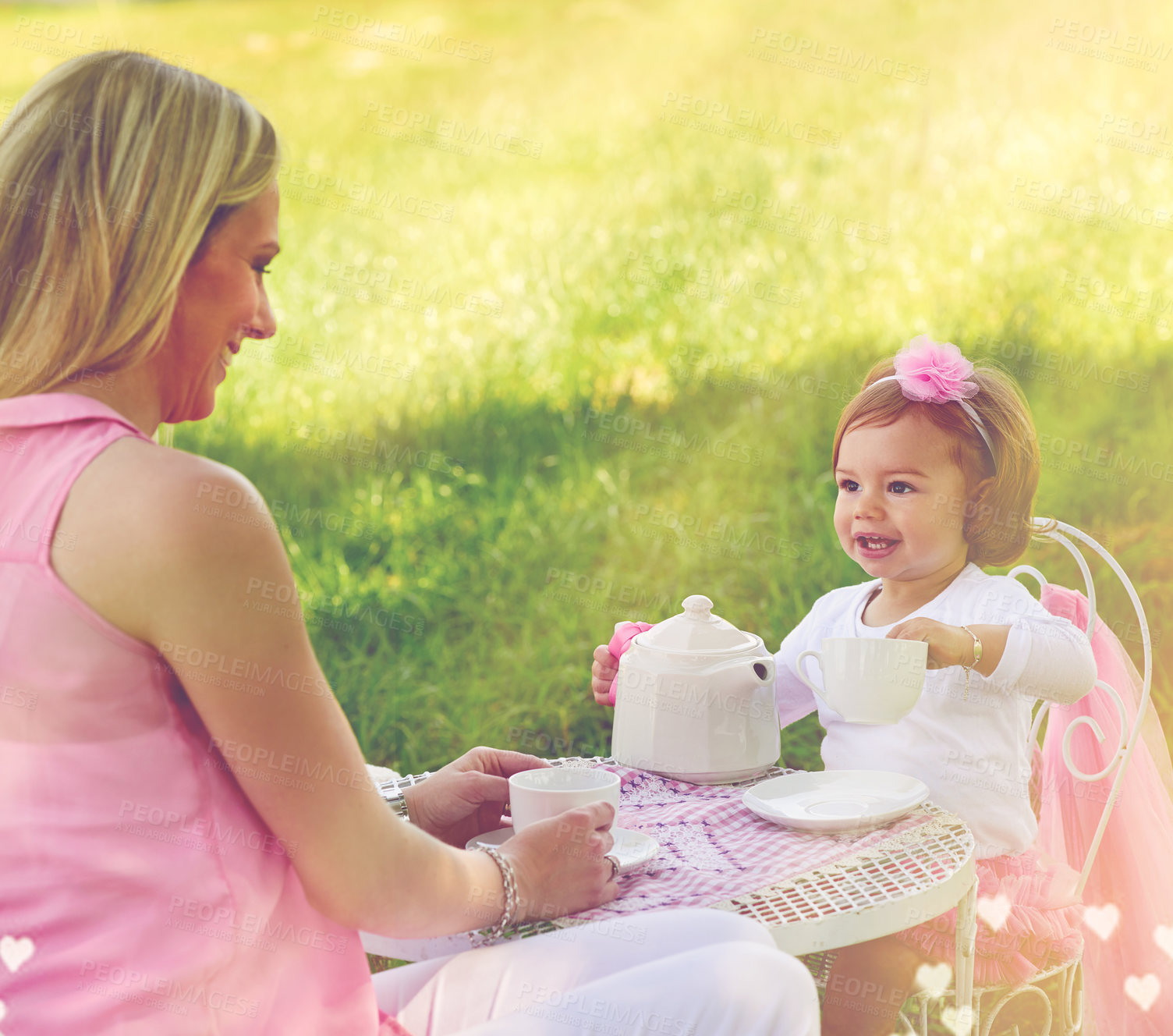 Buy stock photo Shot of a mother and her cute little girl having a tea party on the lawn outside