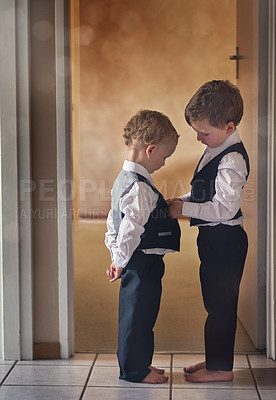 Buy stock photo Shot of a sweet little boy helping his younger brother get dressed in a suit