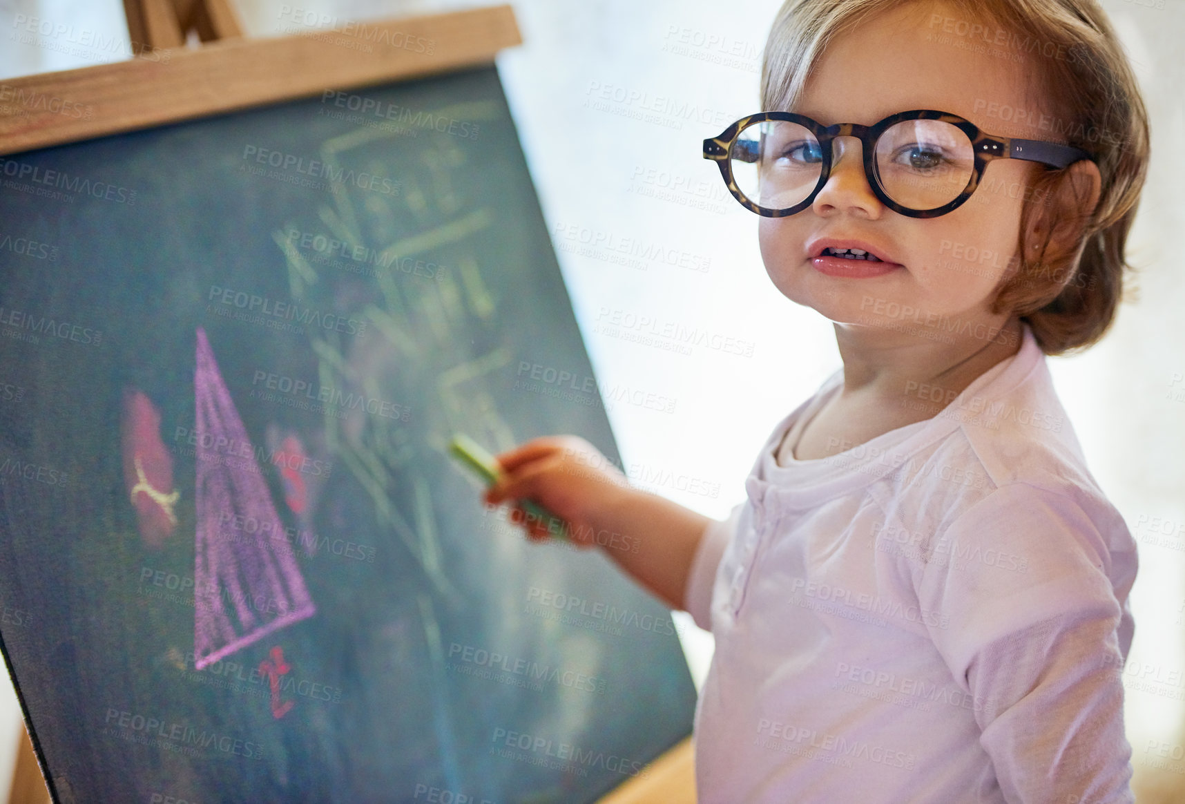 Buy stock photo Portrait of an adorable little girl with big spectacles solving a math problem on a chalkboard at home