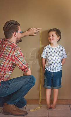 Buy stock photo Shot of a father measuring his little boy's height against a wall at home