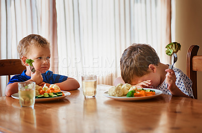 Buy stock photo Shot of two unhappy little boys refusing to eat their vegetables at the dinner table
