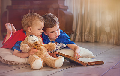 Buy stock photo Shot of two little boys playing with a book while lying on the floor at home