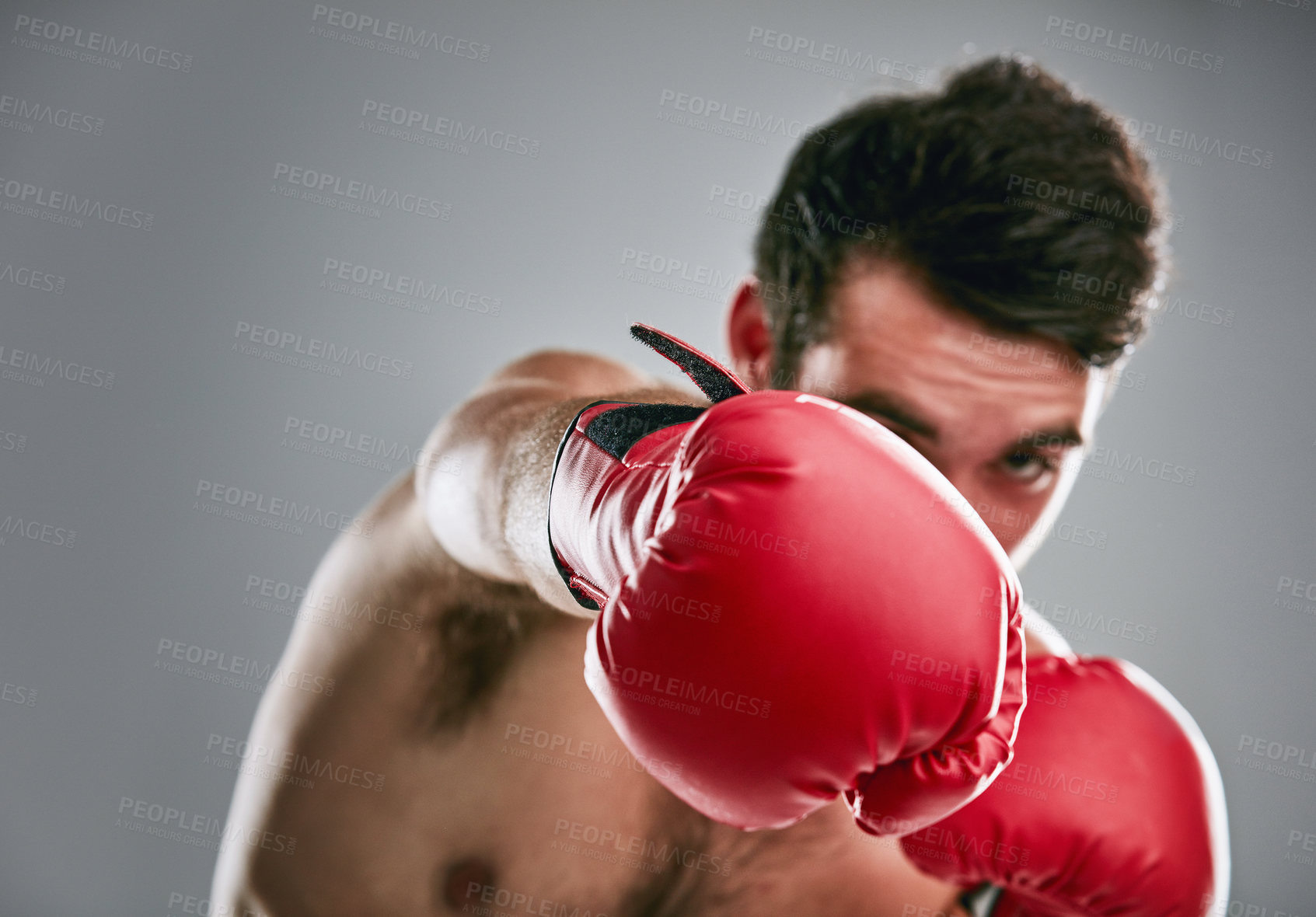 Buy stock photo Studio portrait of a young man boxing against a gray background