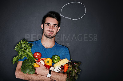 Buy stock photo Studio portrait of a young man carrying vegetables next to an illustration of a thought bubble against a dark background