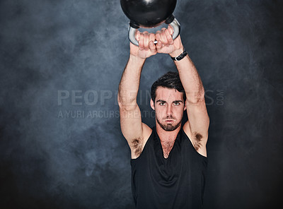 Buy stock photo Studio shot of a young man working out with a kettle bell against a gray background