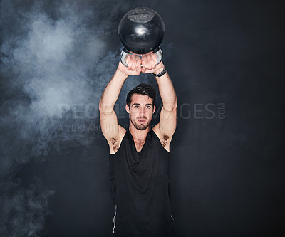 Buy stock photo Studio shot of a young man working out with a kettle bell against a gray background