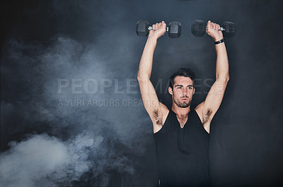 Buy stock photo Studio shot of a young man working out with a dumbbell against a gray background