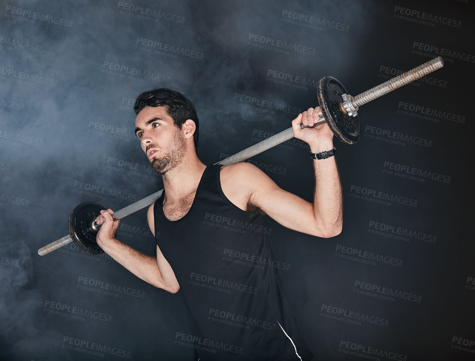 Buy stock photo Studio shot of a young man working out with a barbell against a gray background