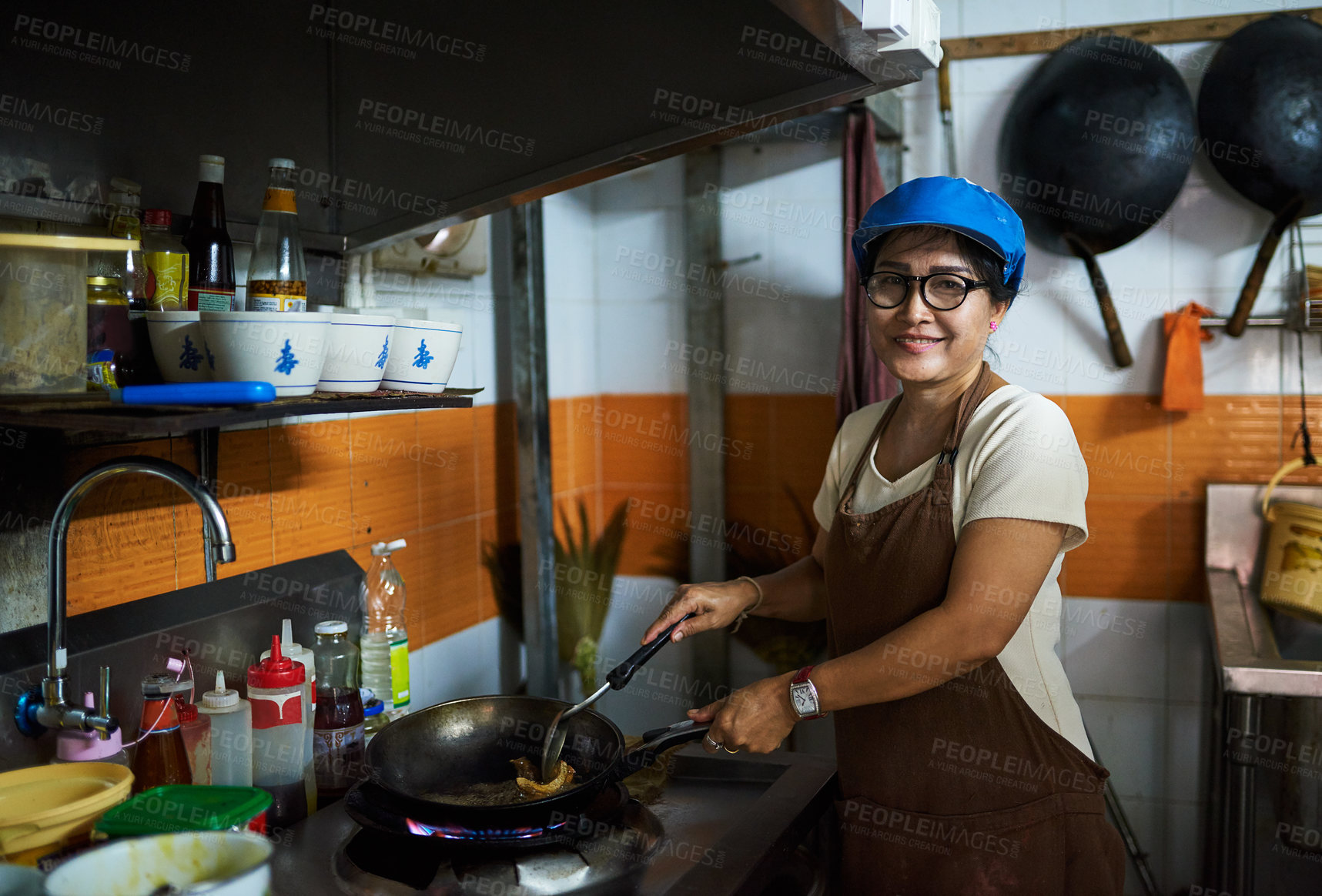 Buy stock photo Portrait of a happy cook frying something in a pan in the kitchen