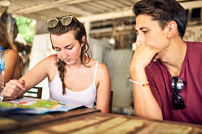 Buy stock photo Shot of two young friends looking at a menu together while relaxing in a restaurant