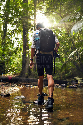 Buy stock photo Rearview shot of an unidentifiable hiker crossing a stream while exploring in the woods