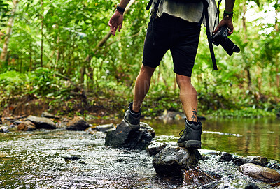 Buy stock photo Cropped shot of an unidentifiable hiker crossing a stream while exploring in the woods