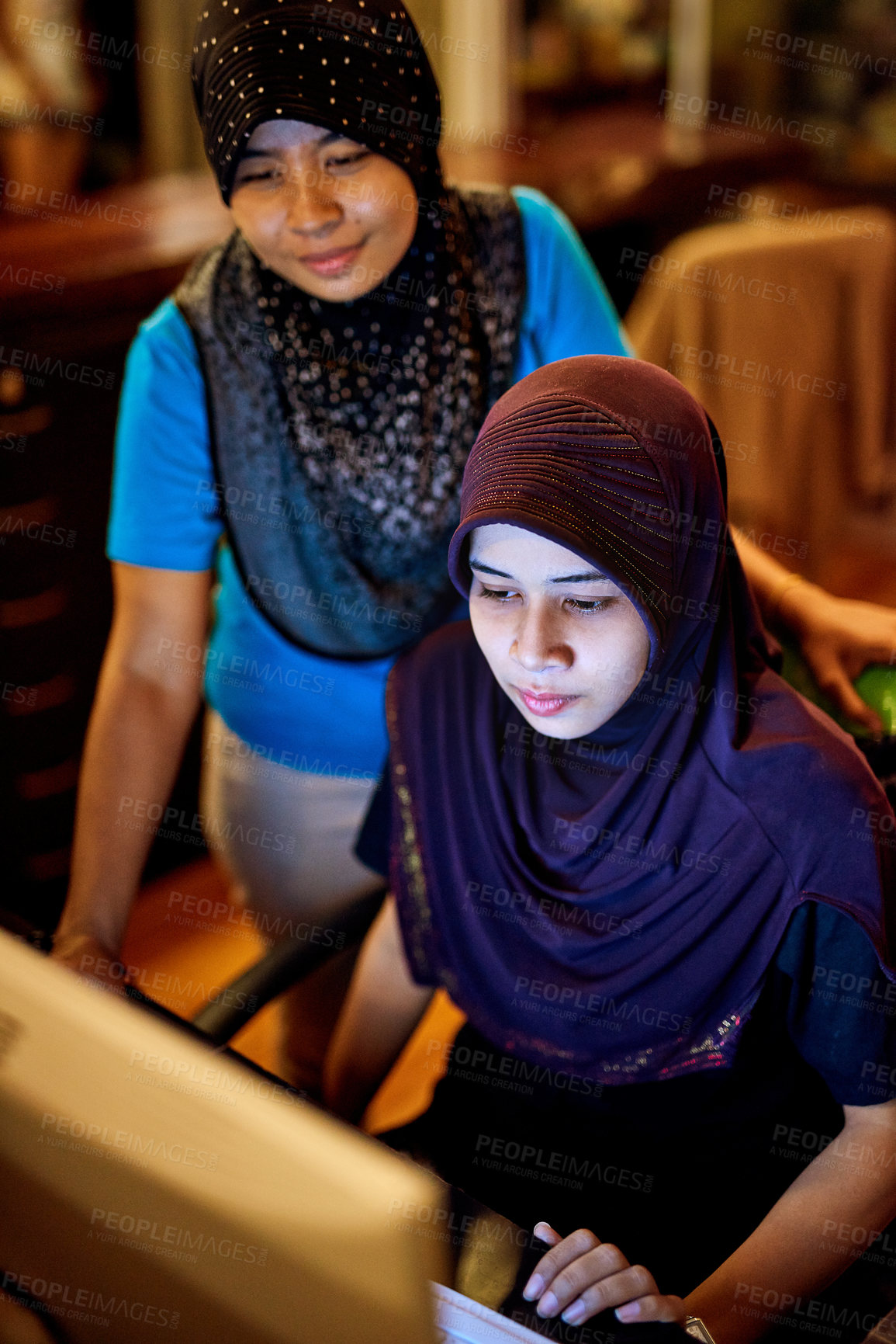 Buy stock photo Shot of two muslim thai women working on a computer at a hotel reception desk