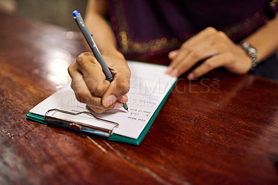 Buy stock photo Closeup shot of a woman filling out a hotel check-in form on a clipboard at a hotel reception counter