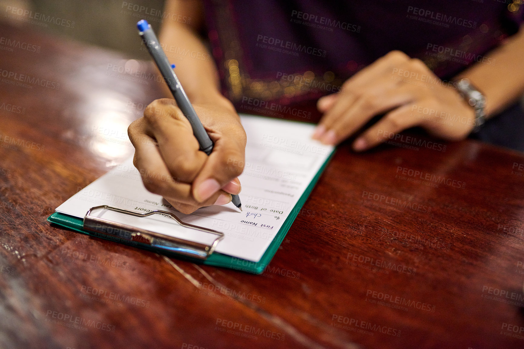 Buy stock photo Closeup shot of a woman filling out a hotel check-in form on a clipboard at a hotel reception counter