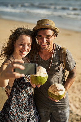 Buy stock photo Couple, smile and selfie for picture on beach for social media update, photography and coconut drink for memory. Happy, man and woman travel to tropical ocean together for summer vacation in Spain