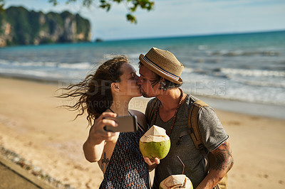 Buy stock photo Couple, kiss and selfie for picture on beach for social media update, photography and coconut drink for memory. Happy, man and woman travel to tropical ocean together for summer vacation in Australia