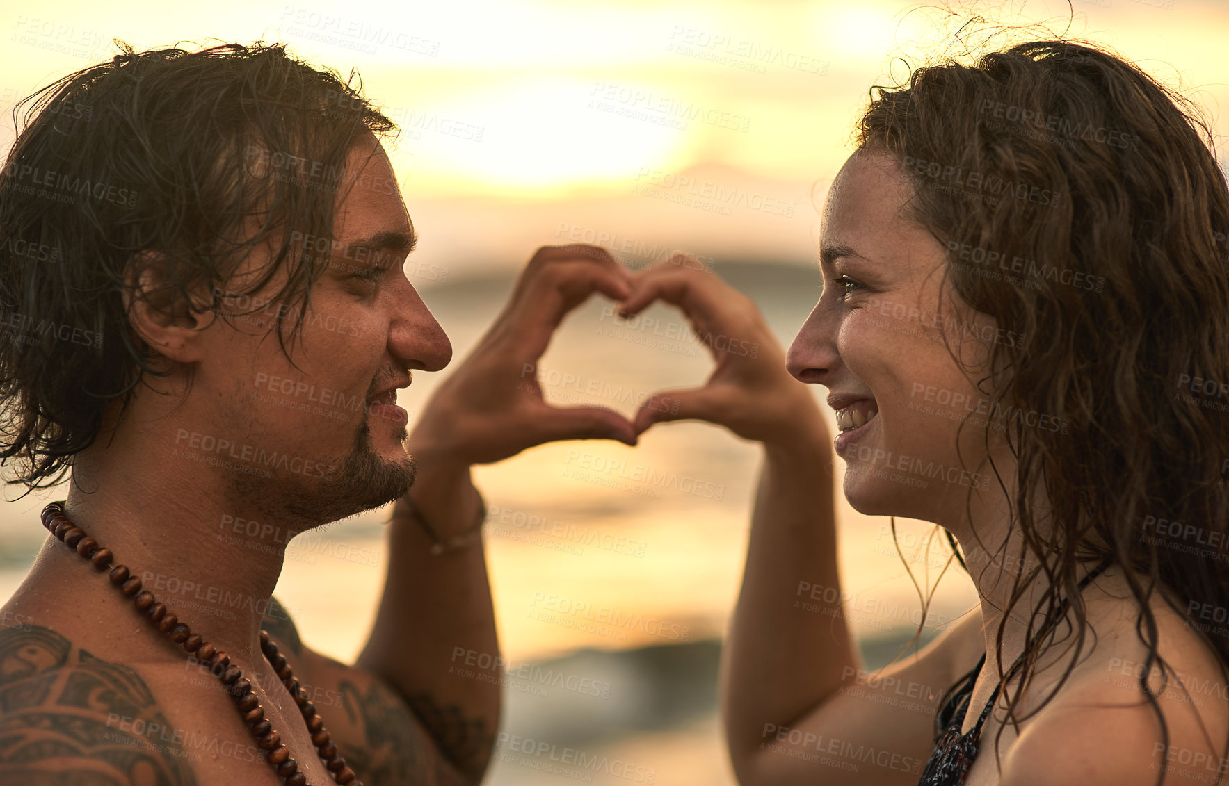 Buy stock photo Shot of a happy young couple posing on a beach at sunset