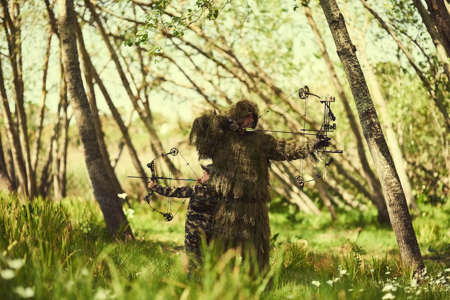 Buy stock photo Shot of a father and son in camouflage hunting with bows and arrows in the woods