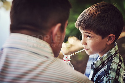 Buy stock photo Shot of a father and his young son sharing a soda while relaxing outside