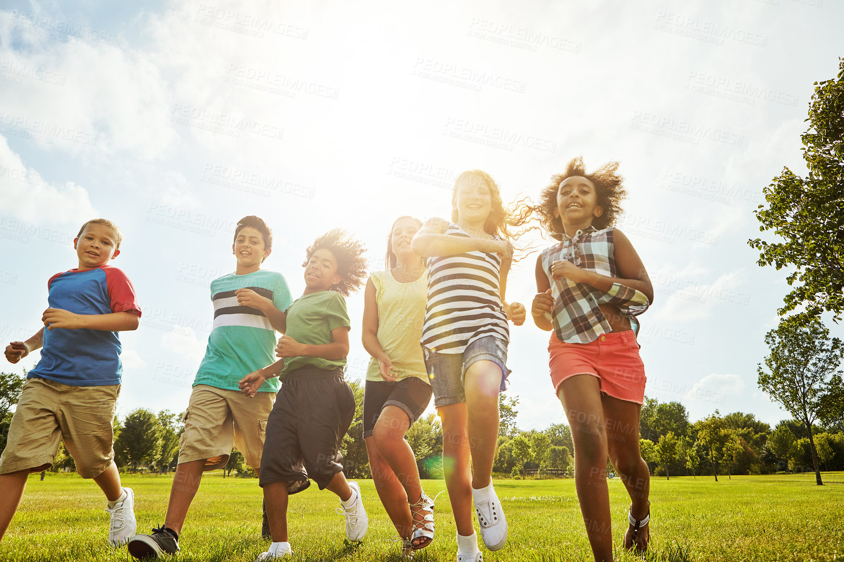 Buy stock photo Happy kids, summer and running with friends in nature for fun, playful day or sunshine at park. Diversity or group of excited children or youth enjoying sunny outdoor holiday on grass field together