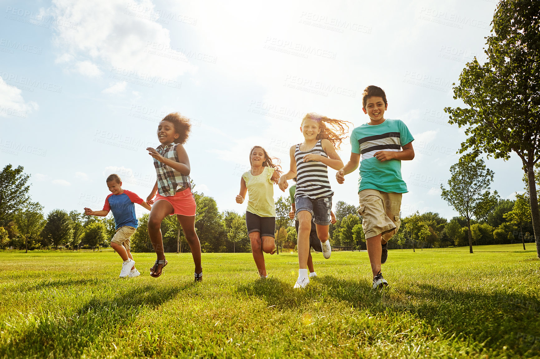 Buy stock photo Happy kids, diversity and running with friends in nature for fun, playful day or summer at park. Group of excited children or youth enjoying sunny outdoor holiday or weekend on grass field together