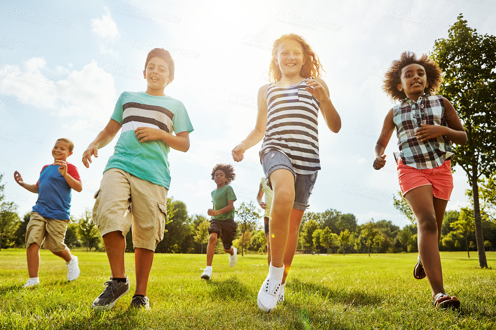 Buy stock photo Happy children, diversity and running with youth in nature for fun, playful day or summer at park. Group of excited kids or friends enjoying sunny outdoor holiday or weekend on grass field together