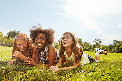 Buy stock photo Shot of three young girls lying together on the grass outside