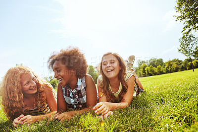 Buy stock photo Shot of three young girls lying together on the grass outside