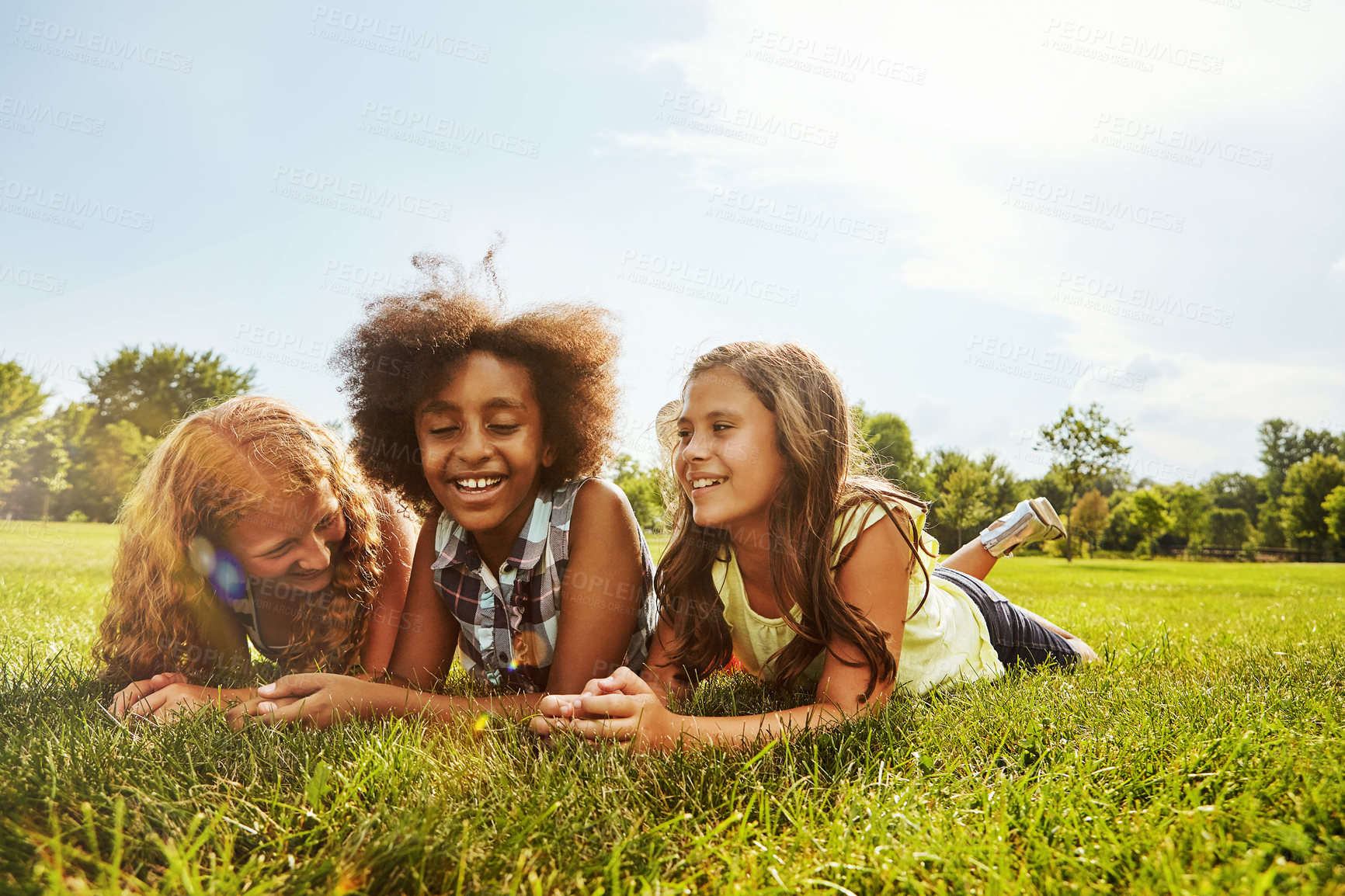 Buy stock photo Girls, laughing and friends on grass, bonding and conversation on break, together and summer holiday. Outdoor, space and children with smile for gossip, relax and funny discussion on weekend at park