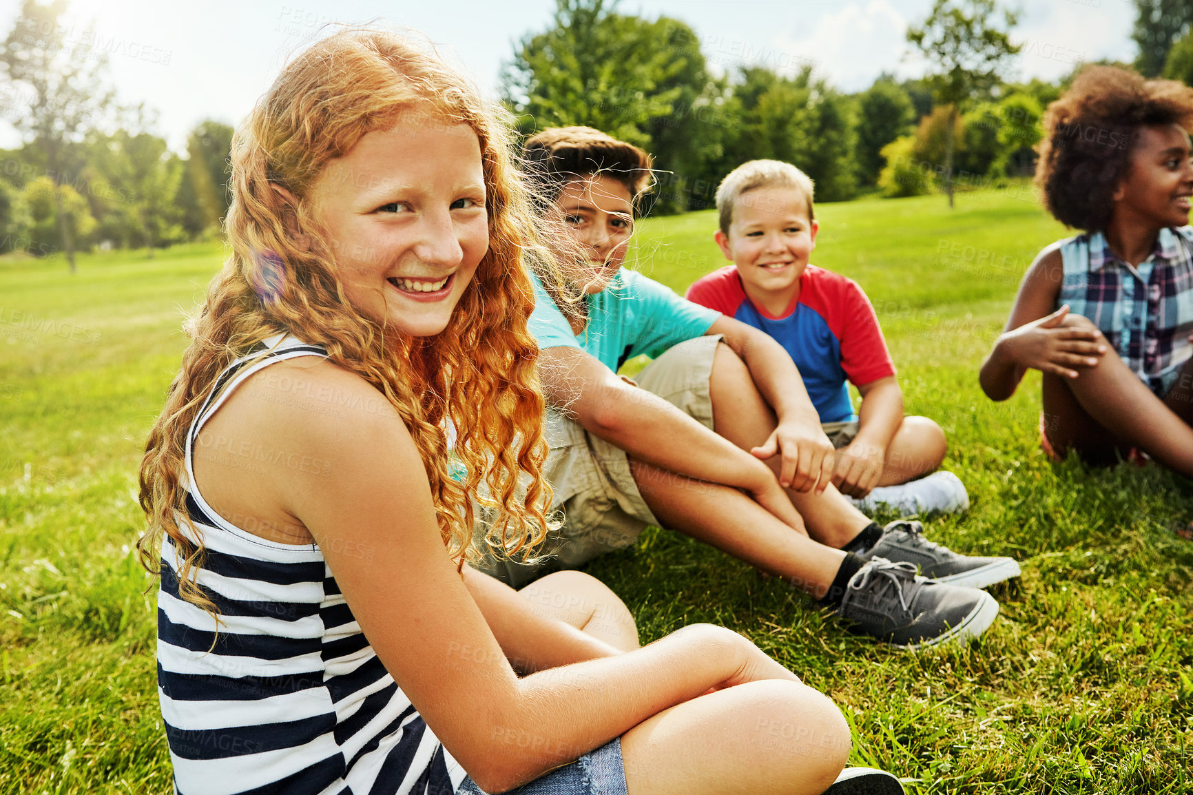 Buy stock photo Portrait of a group of diverse and happy kids sitting together on the grass outside