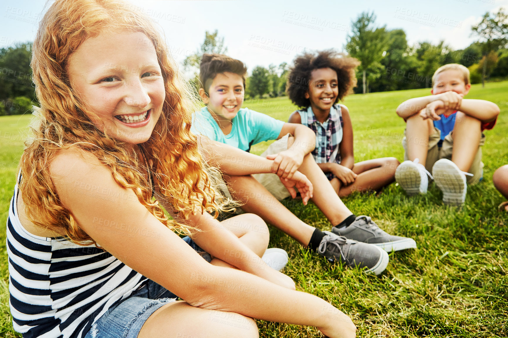 Buy stock photo Portrait of a group of diverse and happy kids sitting together on the grass outside