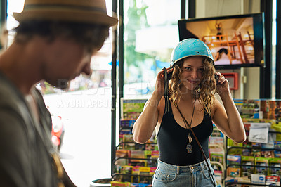 Buy stock photo Portrait of a young woman trying on a motorcycle helmet while standing in a store with her boyfriend