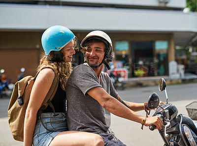 Buy stock photo Shot of two happy backpackers riding a motorcycle through a foreign city