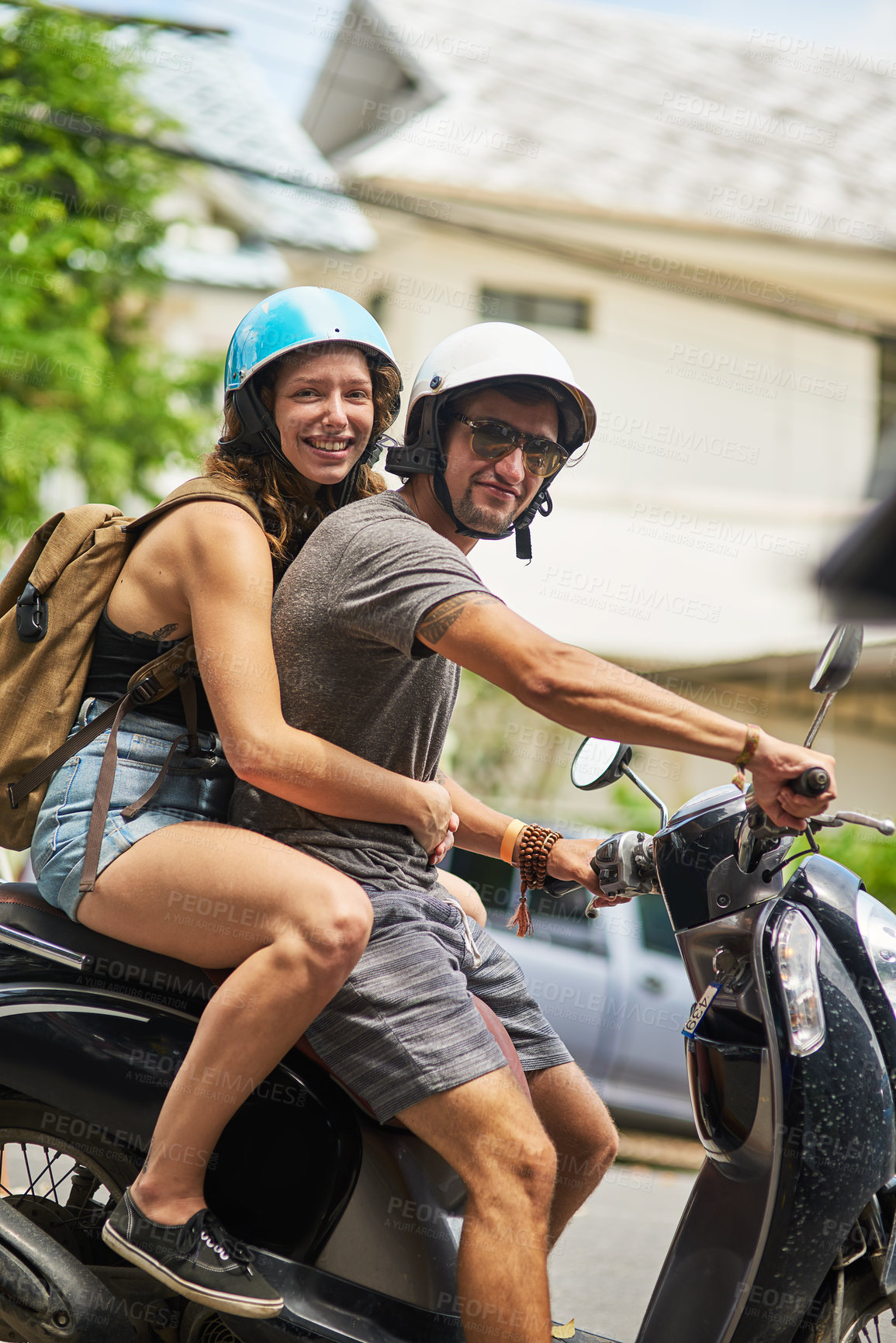 Buy stock photo Portrait of two happy backpackers riding a motorcycle through a foreign city