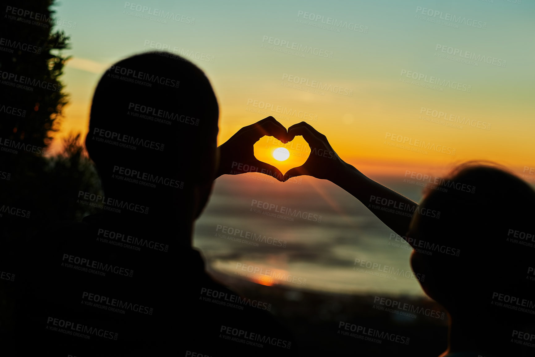 Buy stock photo Rearview shot of two young people making heart shapes with their hands