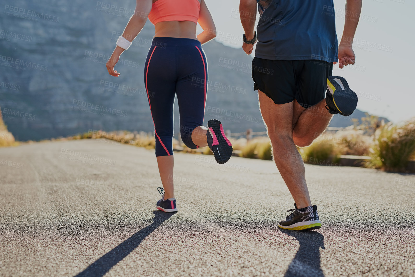 Buy stock photo Rearview shot of two unrecognizable young people running on the road