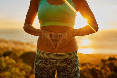 Buy stock photo Shot of an unrecognizable young woman making a heart with her hands on her stomach