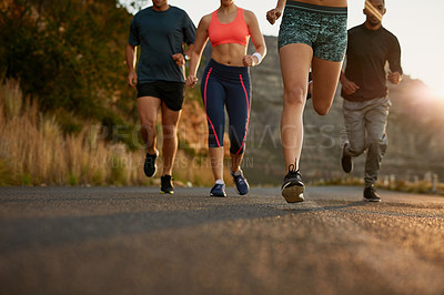 Buy stock photo Cropped shot of a fitness group running along a rural highway