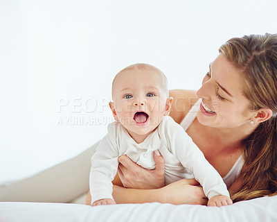 Buy stock photo Loving mother and baby bonding at home, playing while relaxing on a bed together. Happy parent being affectionate with her newborn son, embracing him and sharing precious moments of parenthood
