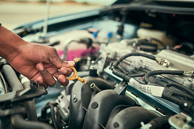 Buy stock photo Cropped shot of a young man checking his engine oil after breaking down