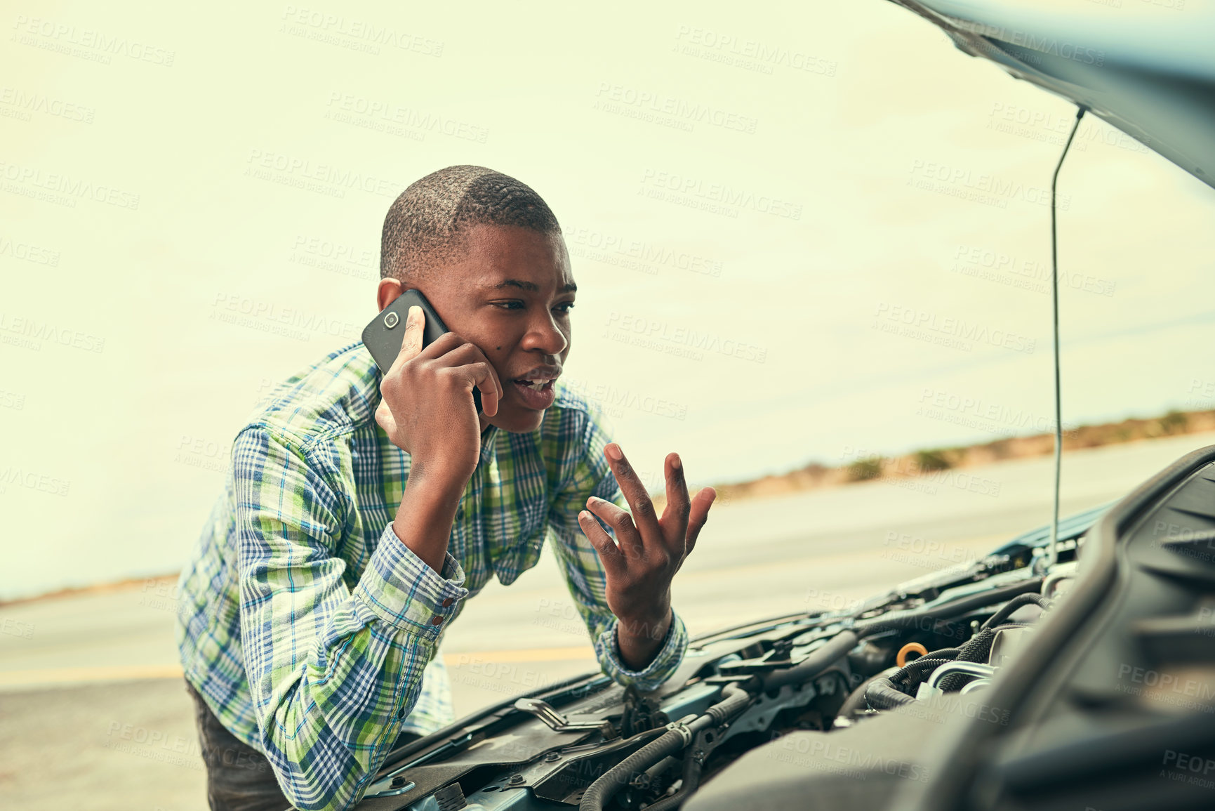 Buy stock photo Cropped shot of a young man calling roadside assistance after breaking down