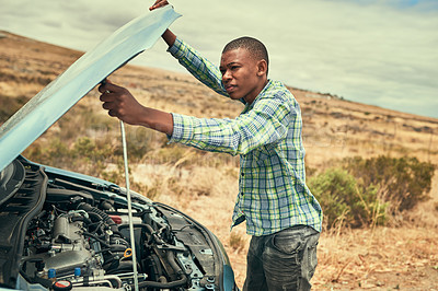 Buy stock photo Cropped shot of a young man checking under the hood of his car after breaking down