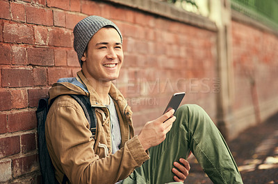 Buy stock photo Asian man, cellphone and city travel or brick wall for outdoor tourism in China or texting, communication or smile. Male person, smartphone and location search on mobile app, journey or direction