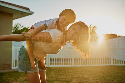 Buy stock photo Shot of a mother and her son enjoying a piggyback ride in their backyard