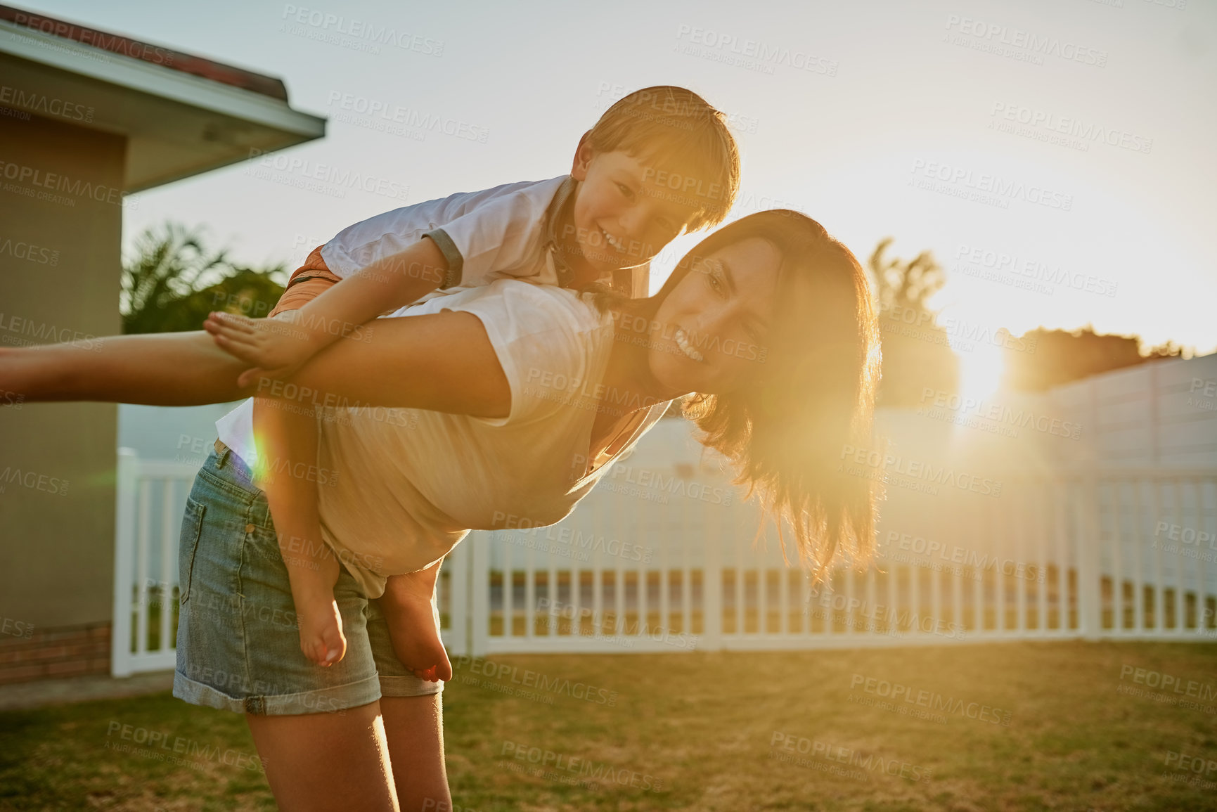 Buy stock photo Shot of a mother and her son enjoying a piggyback ride in their backyard